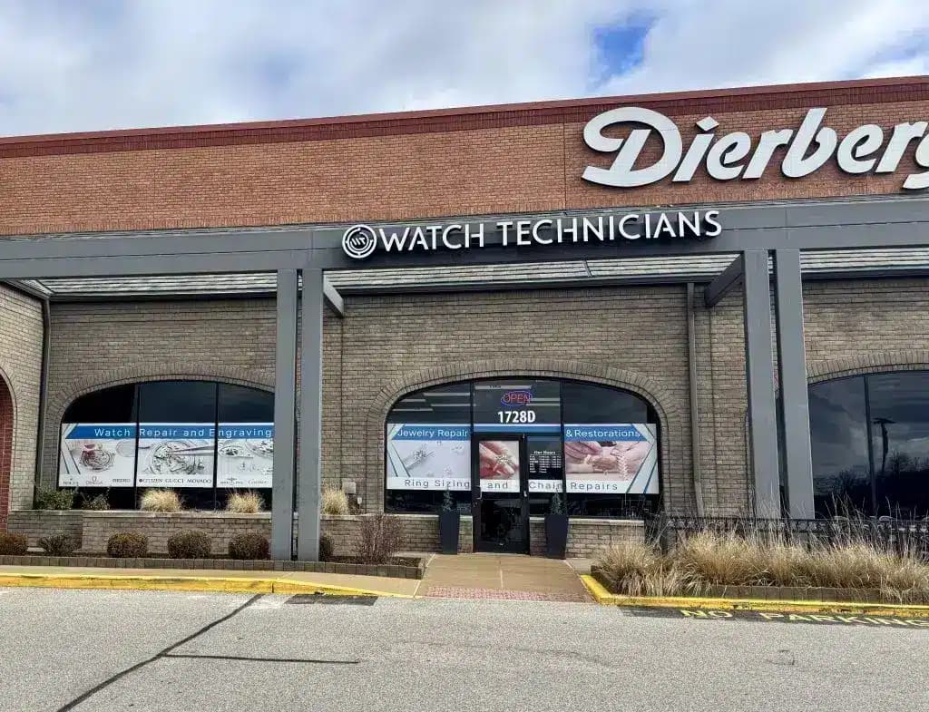 Brick storefront of watch repair shop with large signage and display windows