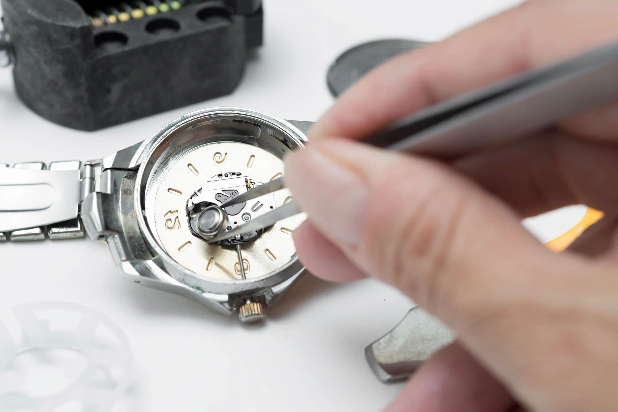 Close-up of watch repair work showing open timepiece mechanism being serviced