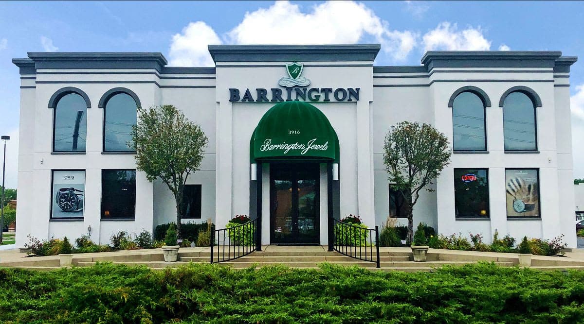White storefront building with green awning and large Barrington Jewels signage, symmetrical arched windows